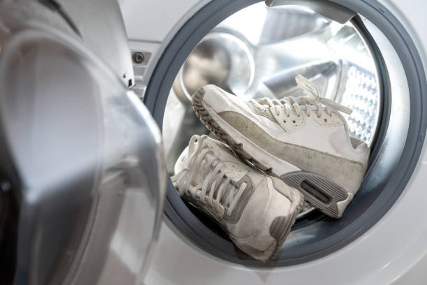 Sneakers exposed in a laundry bag on a washing machine loader